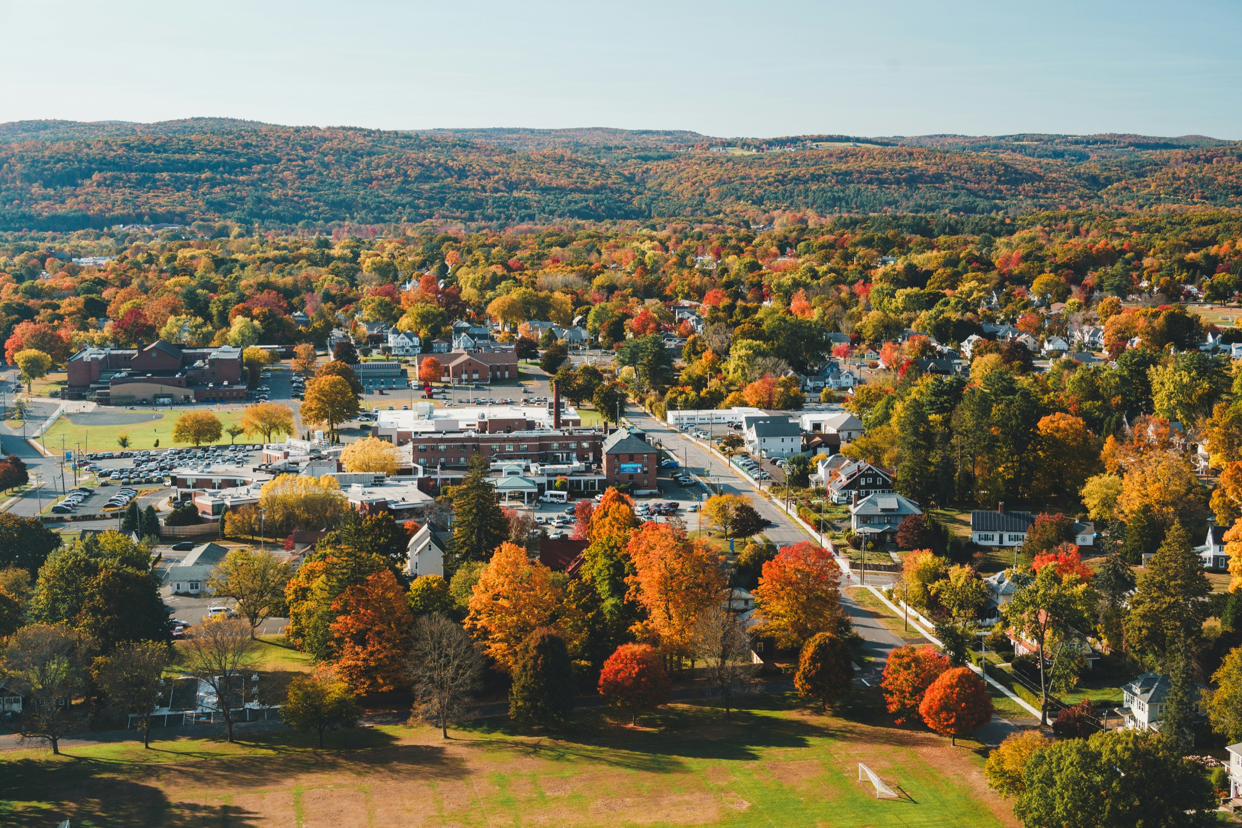 Aerial view of a Massachusetts town surrounded by hills and trees in fall colors.